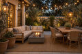 Outdoor patio furniture set in a backyard, featuring a light wood sectional sofa with beige cushions, a rectangular concrete fire pit with glowing flames, a dining table with woven chairs, and warm string lights overhead.